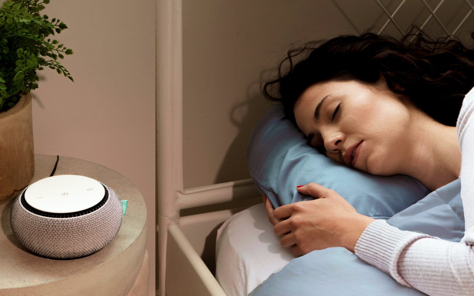 Woman sleeping peacefully next to a white noise machine